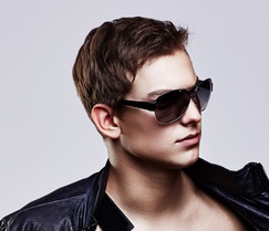 Young handsome macho man in sunglasses with open leather jacket revealing muscular chest and torso